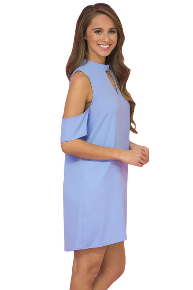 A woman standing, wearing a blue sleeveless mini dress with a V-neckline and half sleeves.